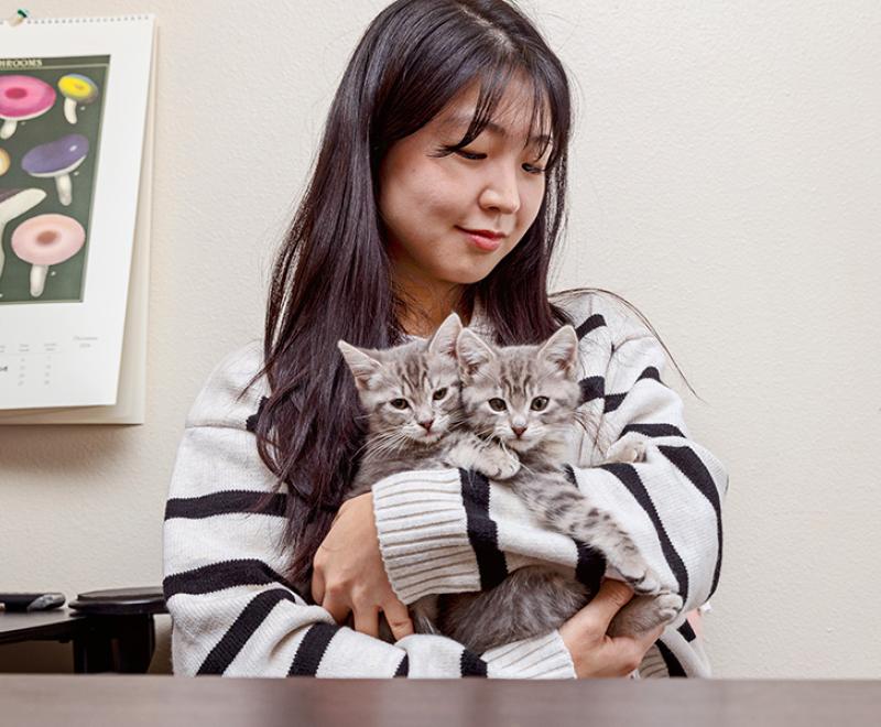 Person cradling two kittens in her arms