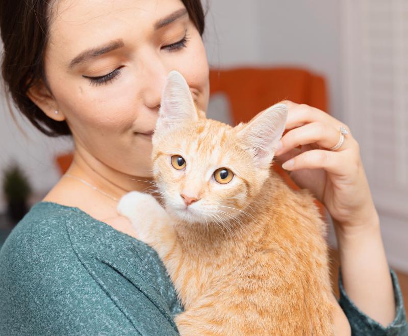 Person smiling while holding a small cat
