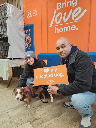 Joseph Bloncourt and Laura Torres adopting Hannibal the dog and holding a I heart my adopted dog sign