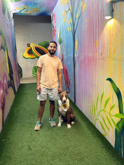 Jonathan and Bolo the dog in a hallway painted with murals