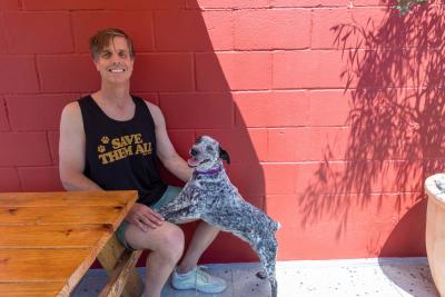 Person at a shaded outside table with his dog