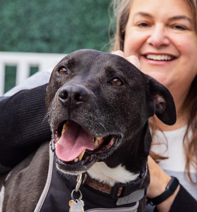Smiling person with happy black dog in front of her