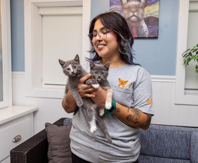 Smiling person holding two tiny kittens in their hands