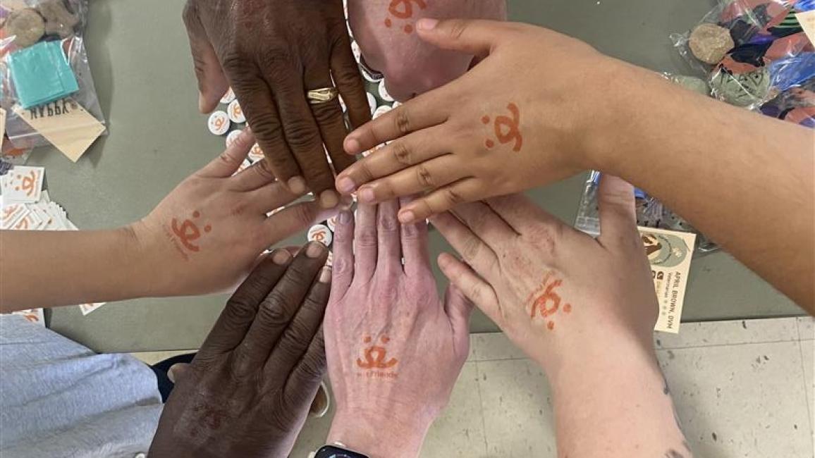 A group of human hands wearing Best Friends logo temporary tattoos all together in a circle