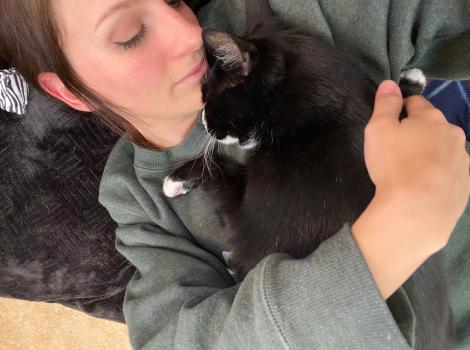 Emily snuggling with Hale the cat, face-to-face, with her arm around him