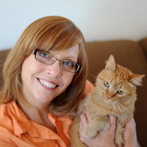 Holly Sizemore sitting on couch holding orange cat
