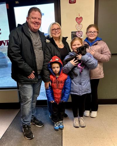 Family holding a black puppy