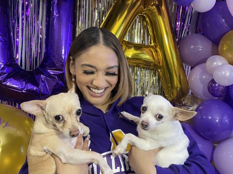 Noemi Peguero holding two Chihuahuas and surrounded by purple balloons