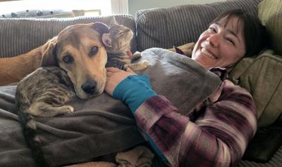 Artemis Chitstrina the Destructor the cat and her dog brother lying on a smiling perseon