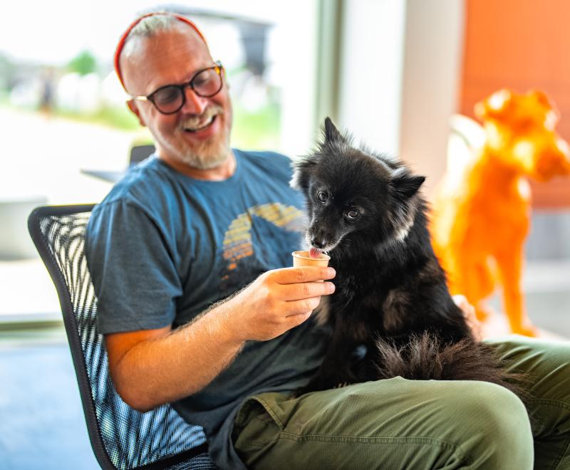 Smiling person giving a dog an ice cream cone at the Best Friends Pet Resource Center in Bentonville Arkansas