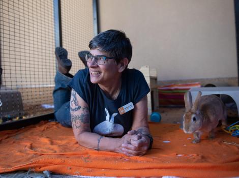Caregiver Sondra Lewis smiling while lying next to Binky the rabbit