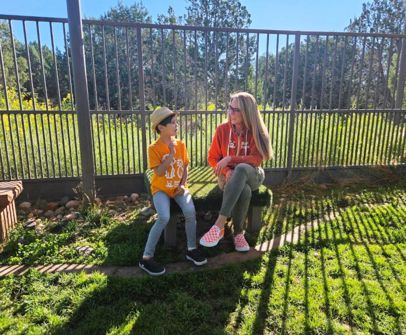 Julian Lin sitting on a bench inside a fence with Best Friends CEO Julie Castle