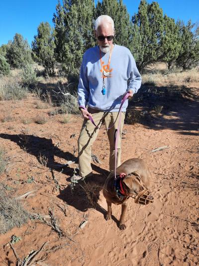 Volunteer Rich Yates outside walking a dog who is wearing a muzzle